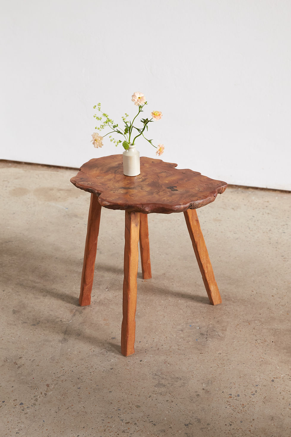A French artisan-made side table, C1960-70, featuring a richly figured burr birch top with an irregular natural edge, set on