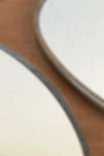 A pair of Italian oval wall mirrors with original mirror plates set within nickel-plated brass frames. The slim frames are fi