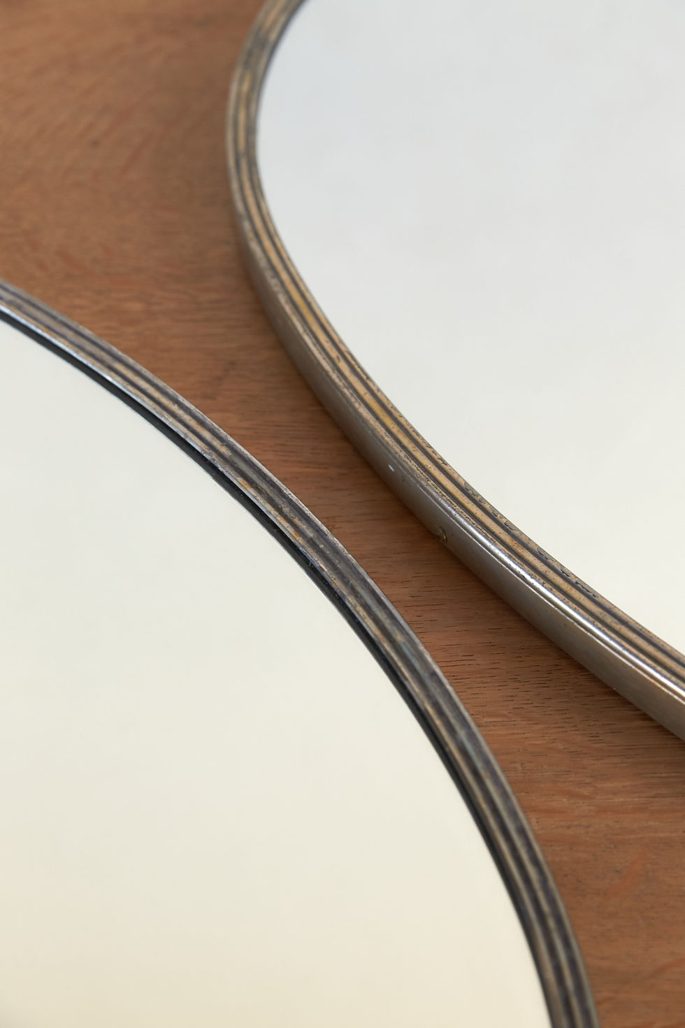 A pair of Italian oval wall mirrors with original mirror plates set within nickel-plated brass frames. The slim frames are fi