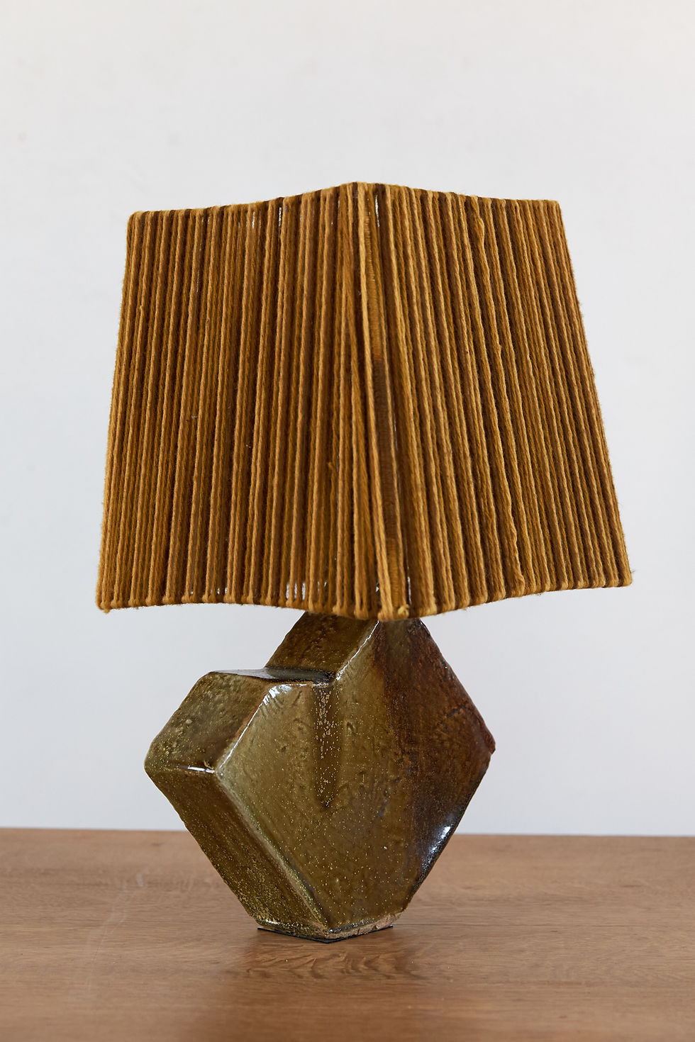 A French studio pottery table lamp with a faceted geometric base finished in a rich olive green and brown glaze, C1970.
