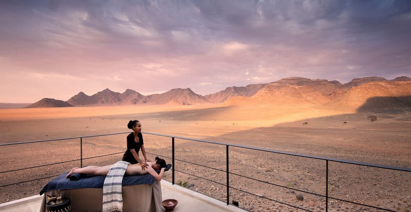 Masseuse giving a female guest a massage on the deck overlooking the desert at Sossusvlei Desert Lodge in Sossusvlei in Namibia
