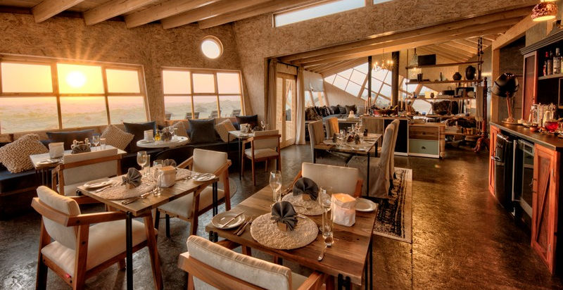2 dining tables laid up for dinner at sunset at Shipwreck Lodge in The Skeleton Coast in Namibia