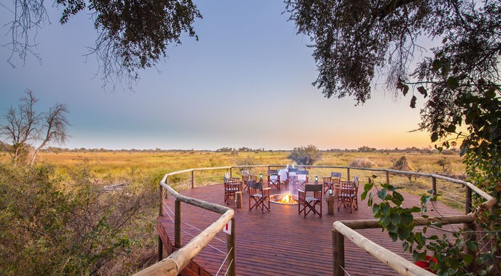 Sunset at the circular deck with chairs around the camp fire at Rra Dinare Safari Camp in The Okavango with Safari Ambitions