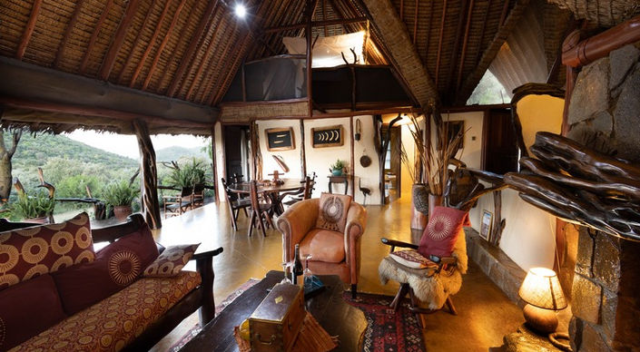 Main guest area with sofas and armchairs in a large wooden area with pitched roof at Saruni Mara Lodge in The North Conservancy, Masai Mara in Kenya