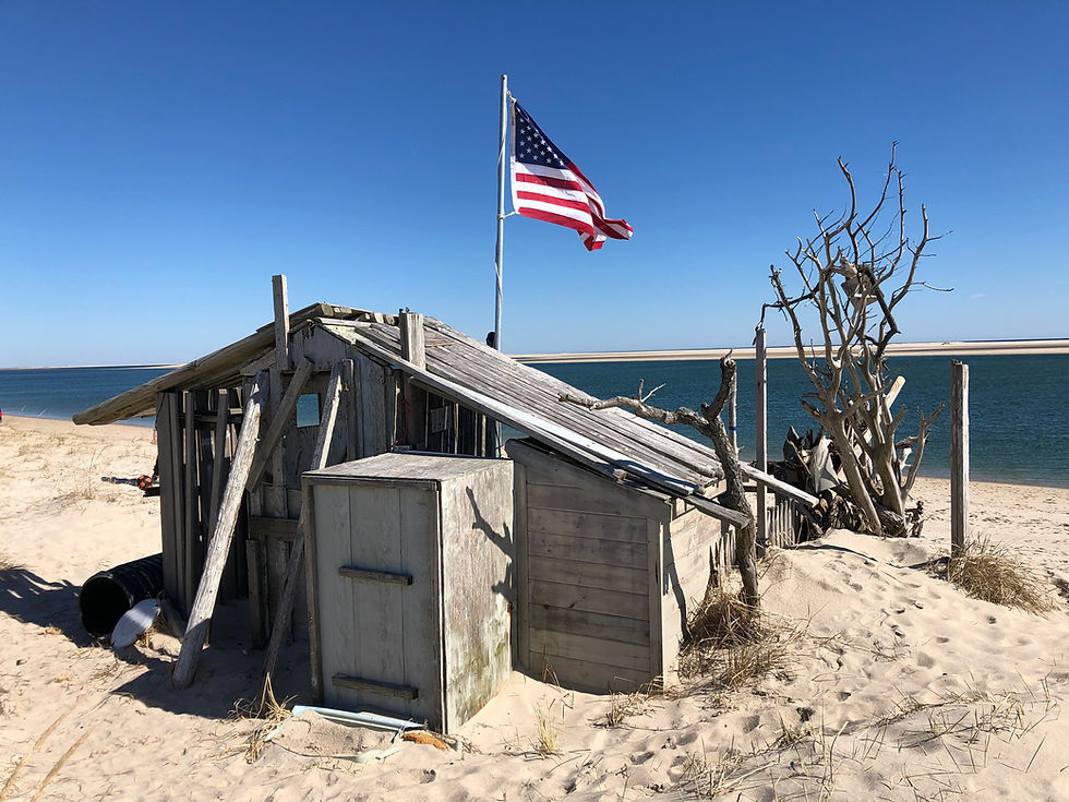 Weathered wooden shack with American flag on a sandy beach