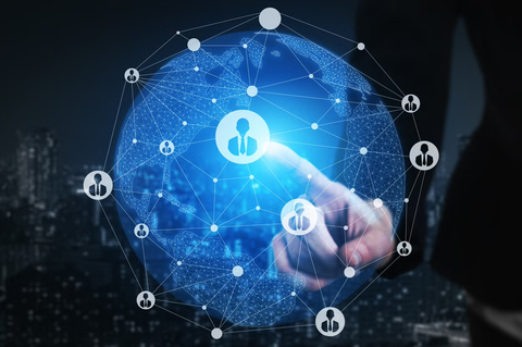 A businessman's finger touches a glowing digital globe overlayed with human resources icons, representing global networking and recruitment