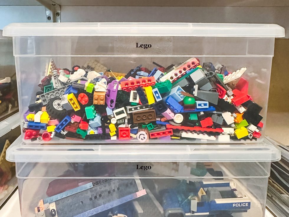 Transparent boxes labeled "Lego" hold colorful, assorted Lego pieces. Shelves in the background. One box contains a police car.