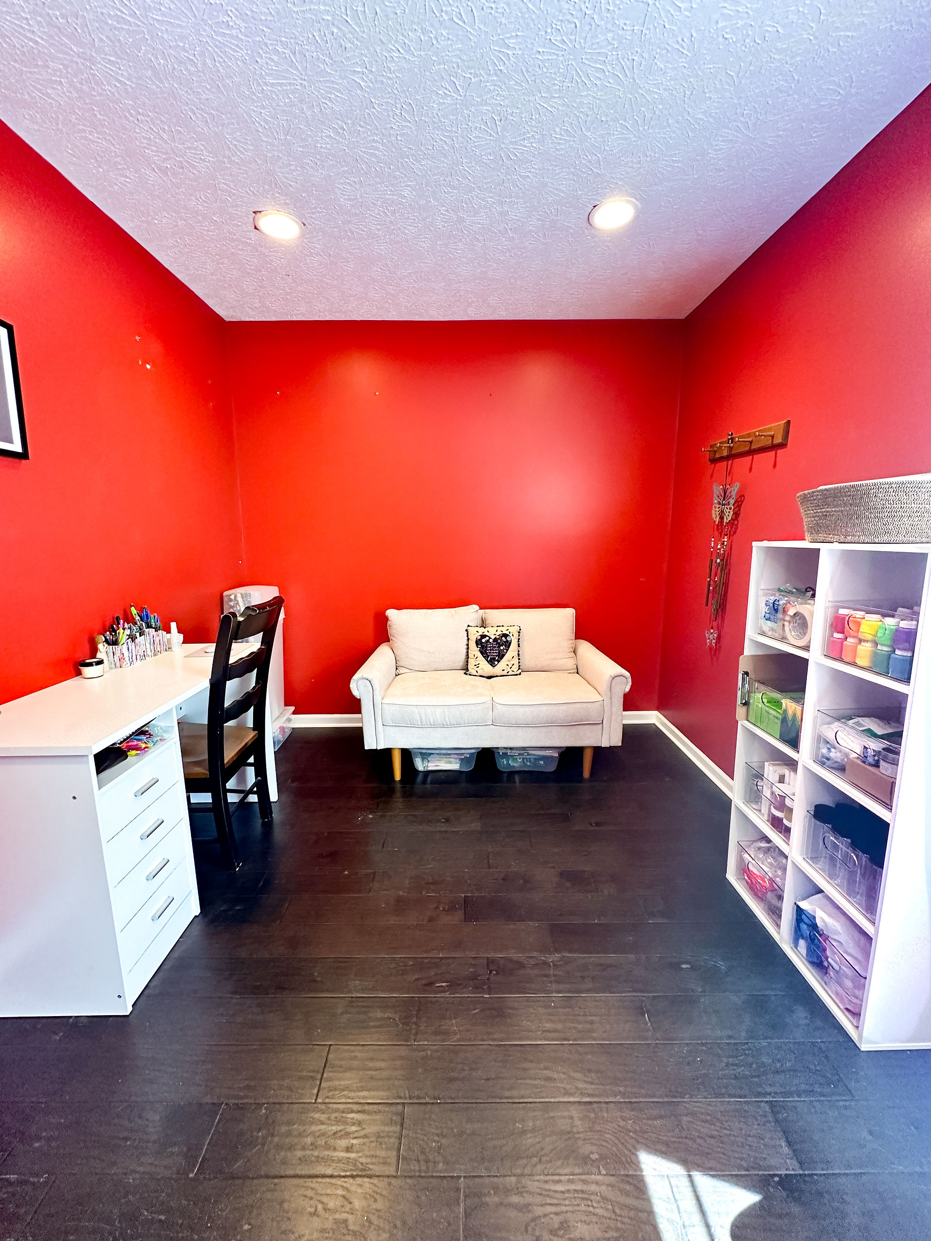 an office that is organized with a desk, couch, and storage self
