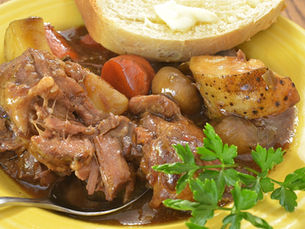Beef stew with carrots and potatoes served beside buttered bread