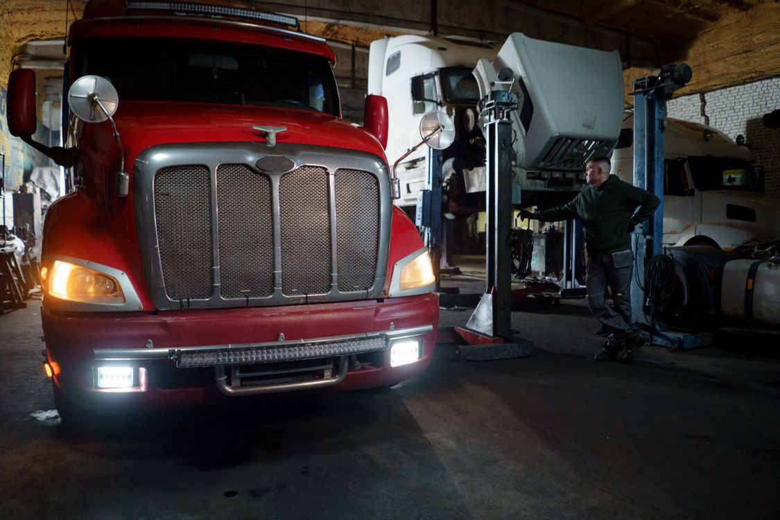 Trucks and a person inside a vehicle workshop.