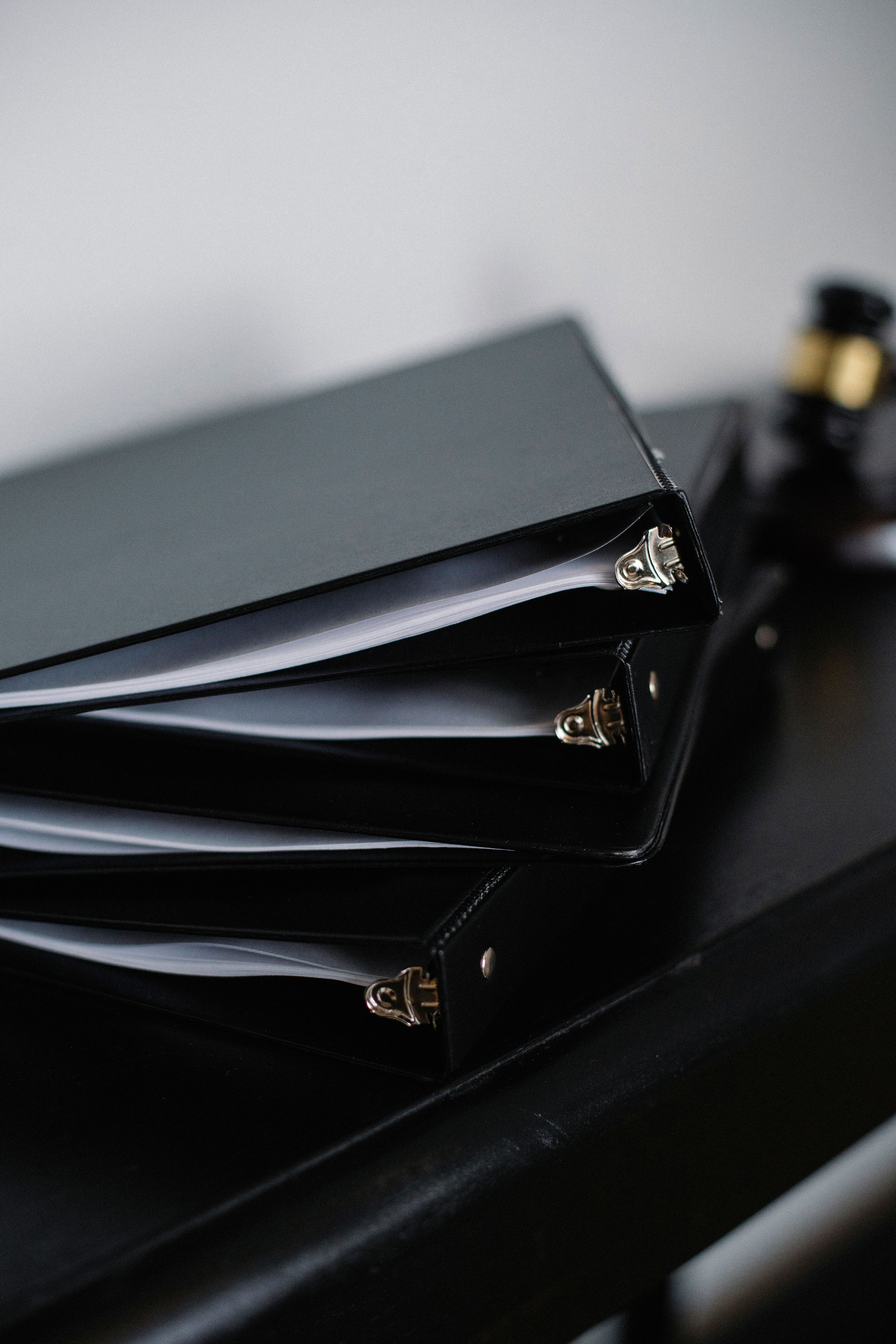 Black document binders stacked on a dark surface.