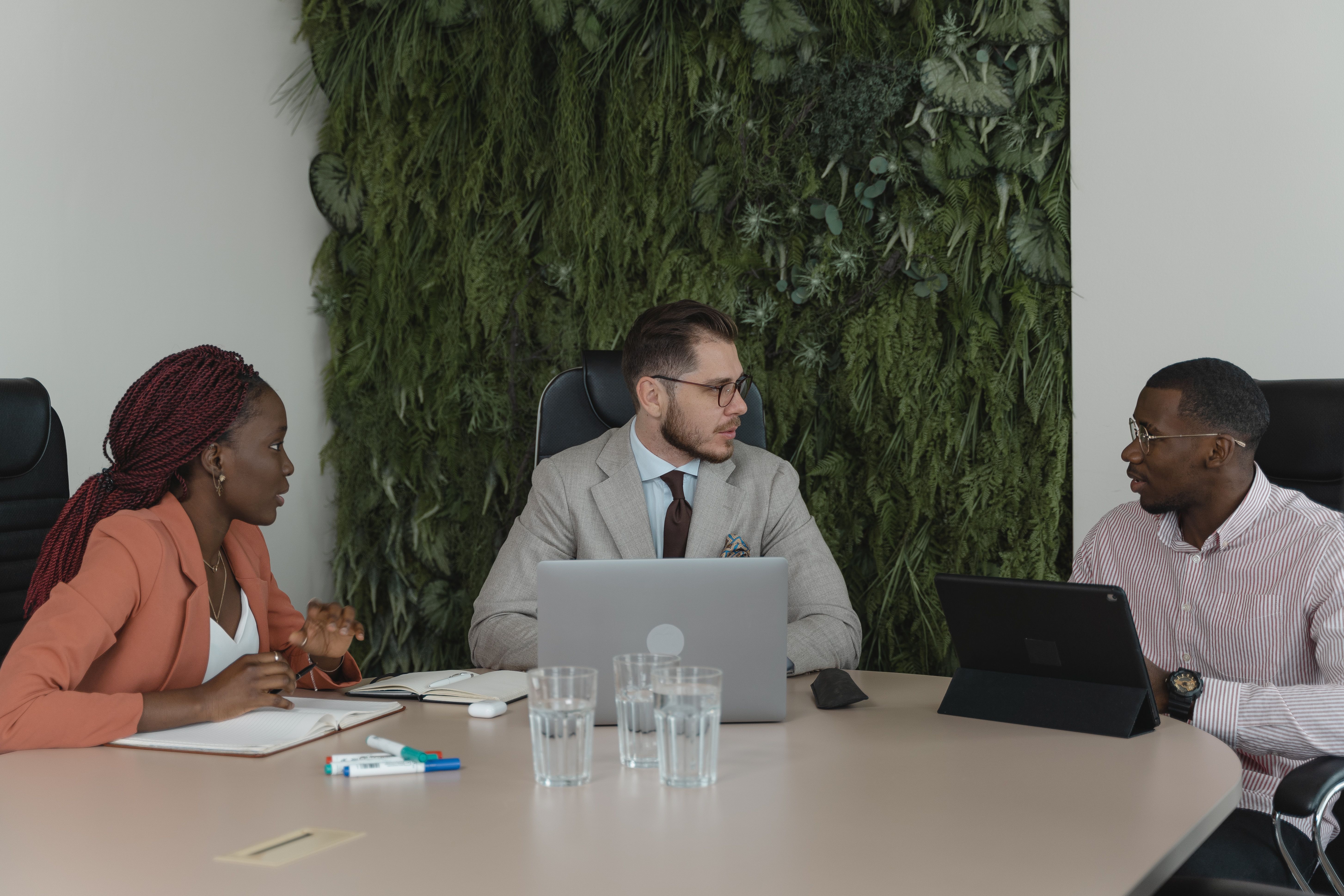 Three people seated around a conference table with laptops and papers.