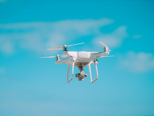 White quadcopter drone hovering in front of a blurred green background