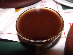 Dark barbecue sauce in a small glass serving bowl
