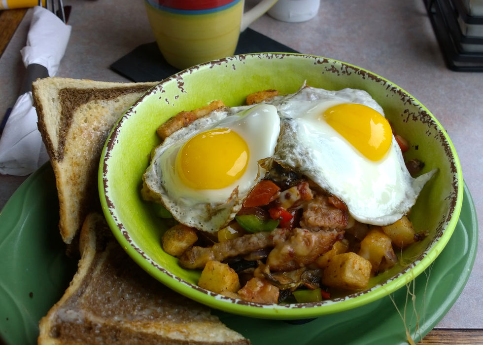 Two fried eggs over a bowl of potato breakfast hash, with toast alongside.