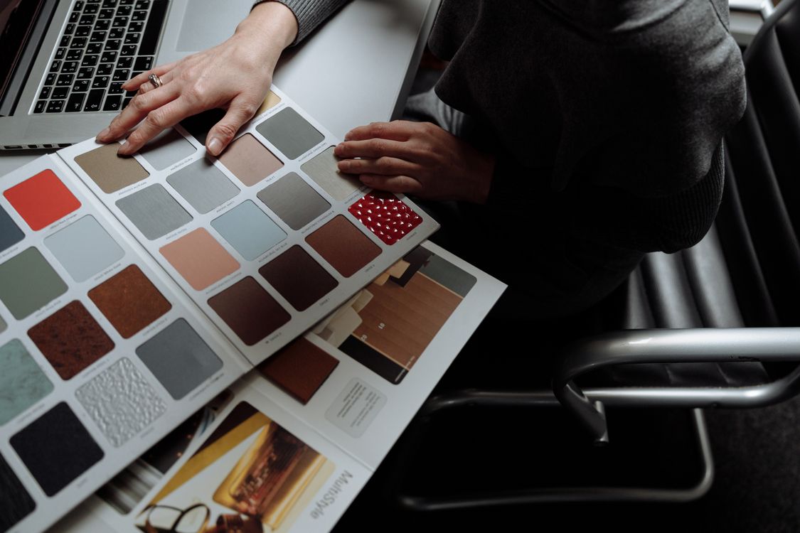 Hands reviewing color swatches beside an open laptop.