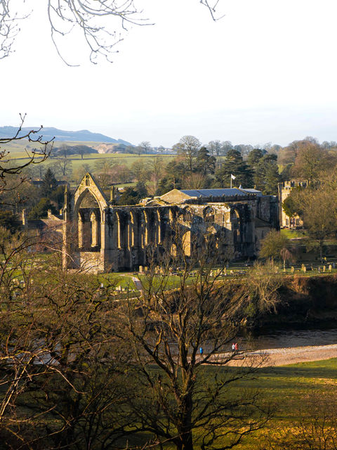 This image shows Bolton Abbey and Priory from a raised position during the golden hour of sunrise.