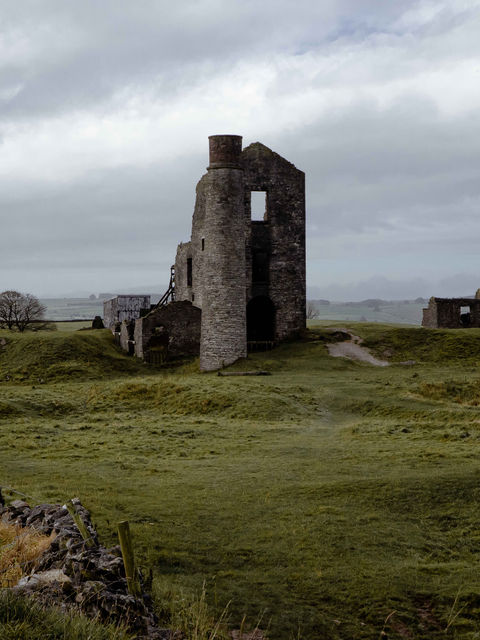 The image shows the main stack of the Magpie Mine and central tower from a distance, with green and yellow fields in the foreground.