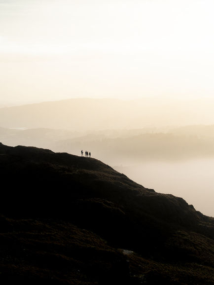 Amidst A Slowly Setting Sun, Four Hikers Pause For A Moment Of Reflection. The Lake District, UK