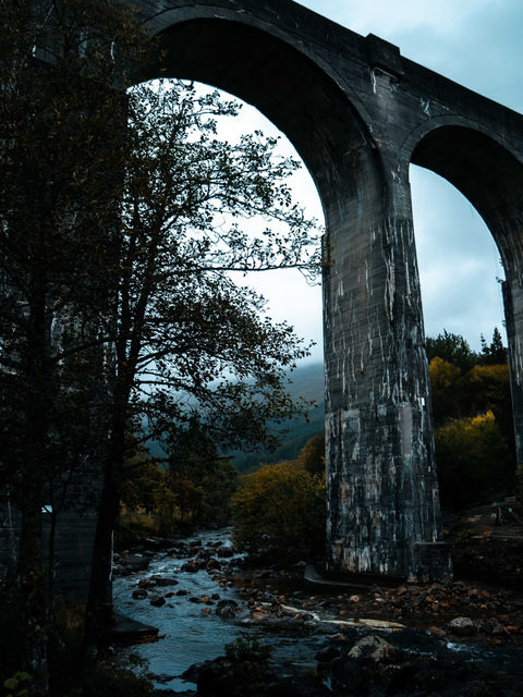 The image shows a picture from ground level by the side of the River Finnan, looking up to the viaduct itself.
