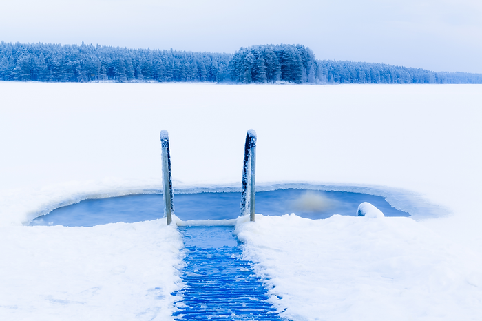 Typisches Eisloch für Winterbaden in Finnland: ein zugefrorener See, umgeben von verschneiter Landschaft und frostiger Stille.