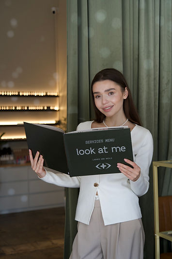Woman holding Look At Me service menu in a studio