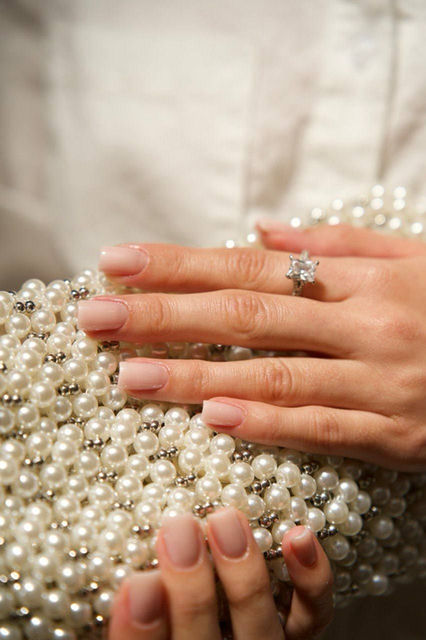 Nude manicure and diamond ring on pearl clutch