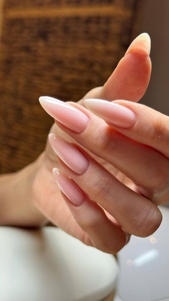 Long almond-shaped nude nails on a hand