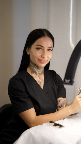 Portrait of a smiling beautician with tattoos in a studio