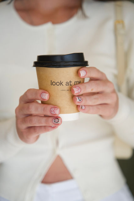 Manicured hands with nail art holding a coffee cup