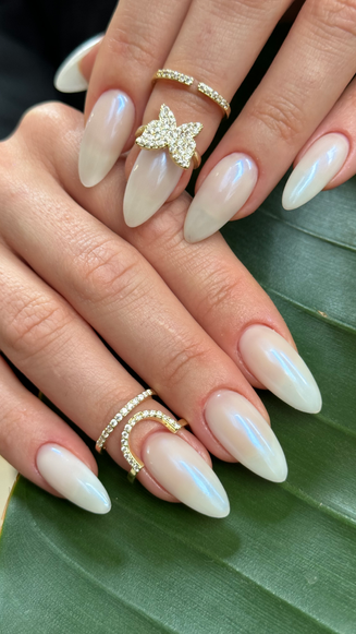 Almond-shaped iridescent white nails with butterfly jewelry