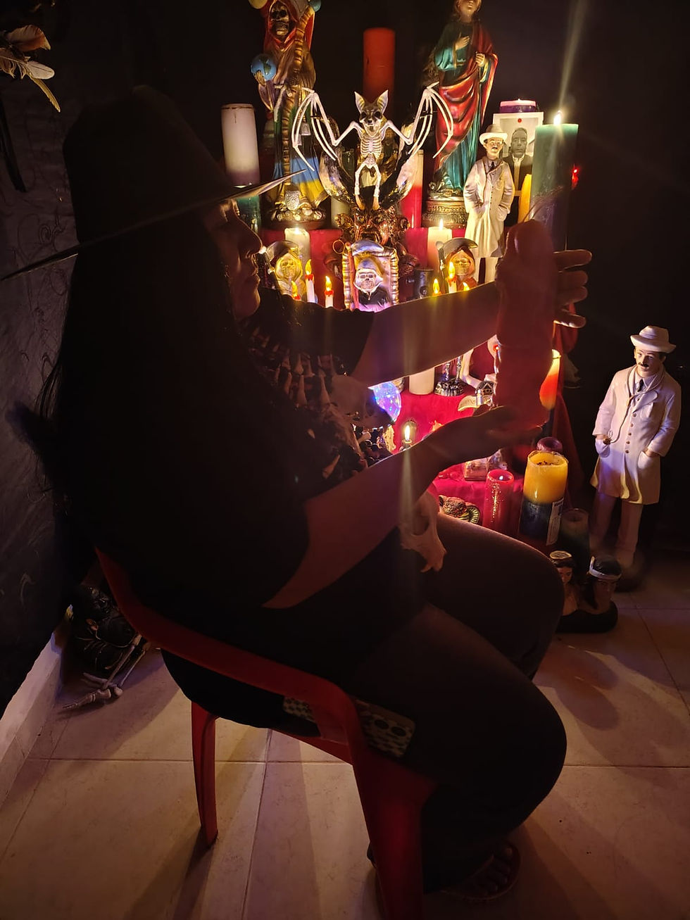 Maestra Victoria realizando un ritual espiritual frente a un altar con velas e imágenes místicas.