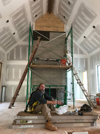 Kevin Schreiber in Unfinished Great Room Working With Large Fire Place Tile - Daniel Builders