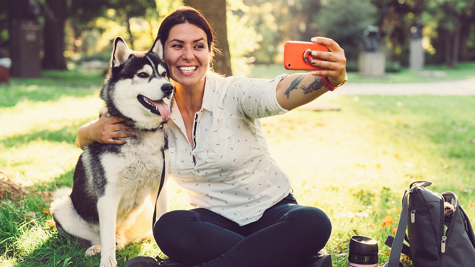 A woman taking a selfie with her Husky dog in a park