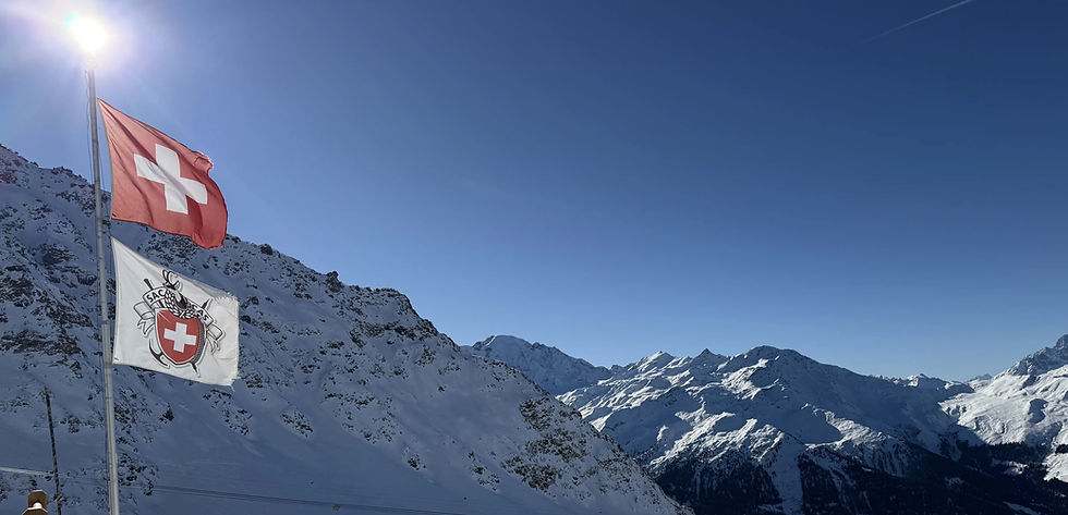Zwitserse vlag wappert boven de besneeuwde pistes en bergen van skigebied Verbier in Zwitserland.