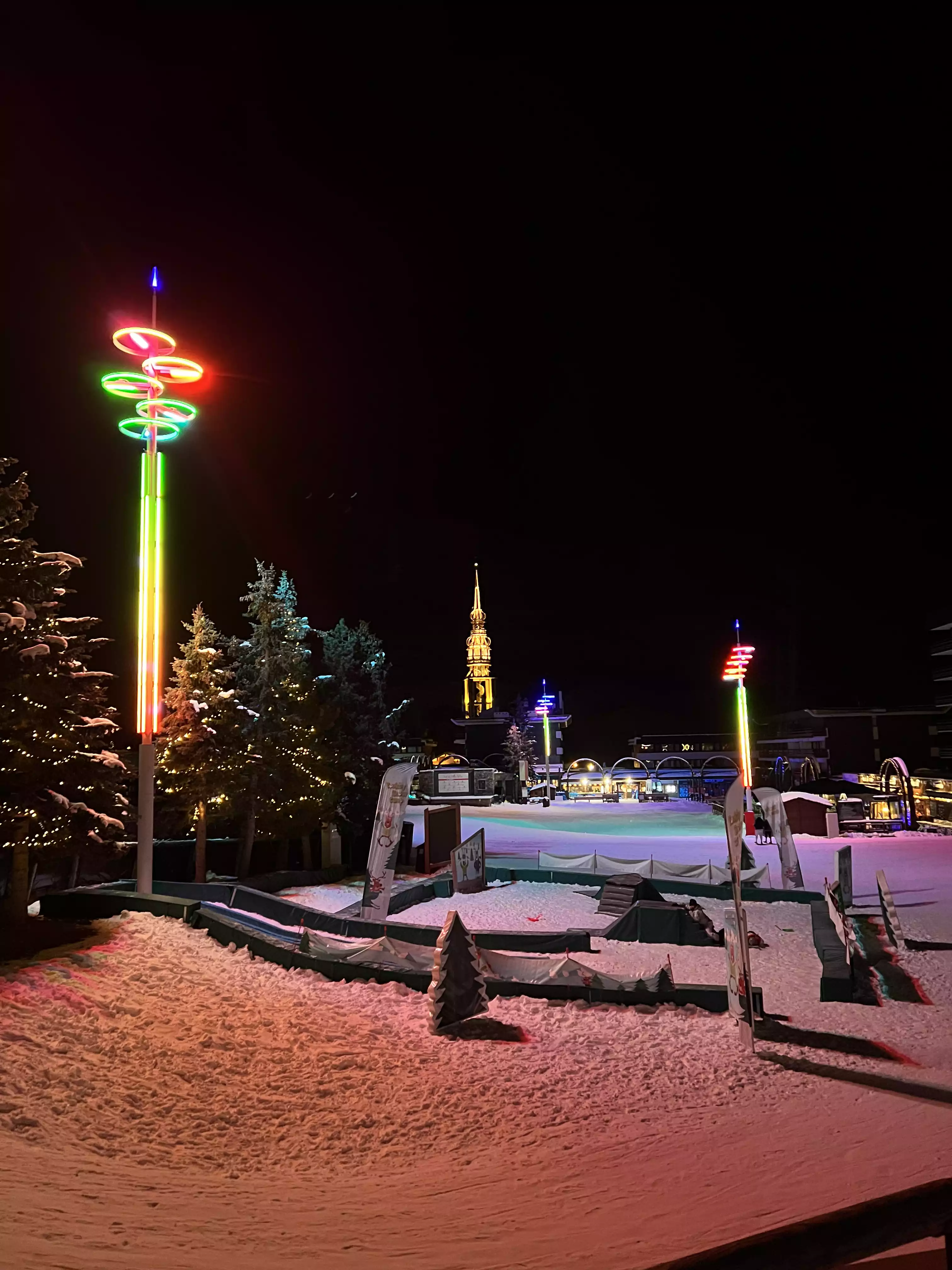 Les Menuires in de avond met gekleurde verlichting en de verlichte toren
