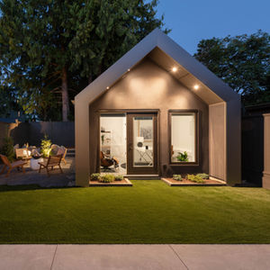 Rear accessory building with a simple contemporary gable roof, double doors, and clean modern cladding at the backyard edge.