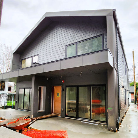 Courtyard view of Building 2 showing a covered patio edge, large sliding doors, and the shared open space between the two duplex buildings.