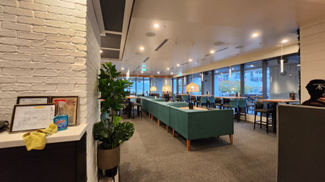 Interior view of the dining room with a long banquette, open aisle, and sightlines toward the service and kitchen areas.