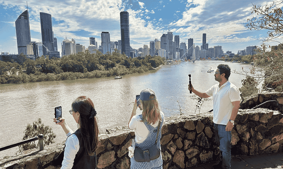 Three people at the top of a lookout. The river and city skyline is behind them.