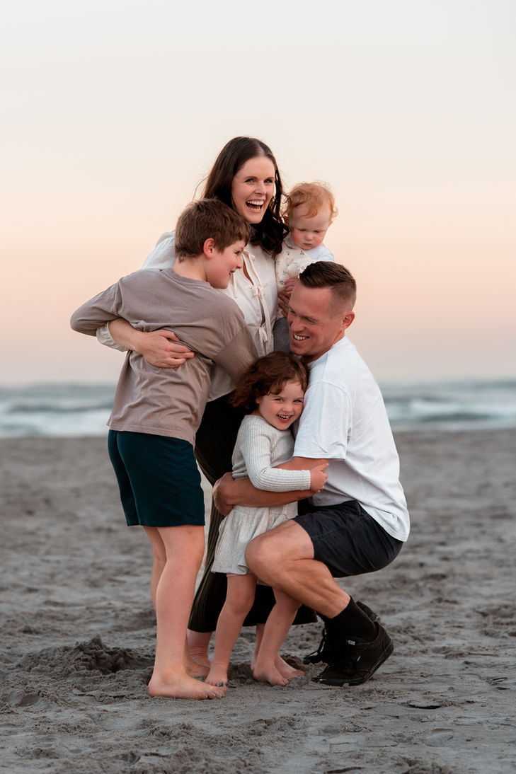 Kids running up and giving their parents a big cuddle during a lifestyle family photo session with Dunedin Photographer, Nakita Marx Photography.