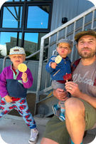 Man and two young boys holding smiley faced popsicles