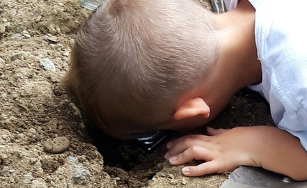 Kind, das den Erdboden nach Tierchen untersucht