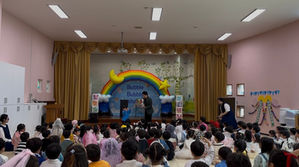 유치원 무대에서 공연을 하고 있는 마술사의 모습과 백 여명의 아이들이 관람하는모습 