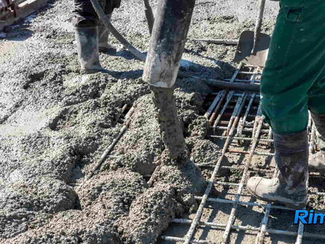Workers placing Rimix3D macro synthetic fiber reinforced concrete using a pump line over steel mesh reinforcement for a slab-on-ground.