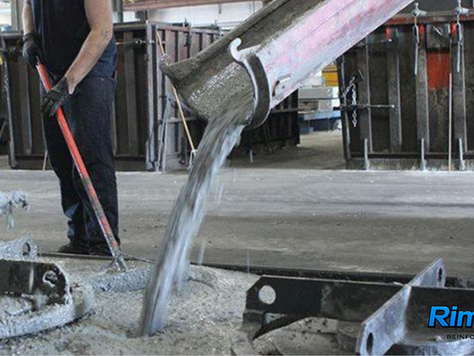 Workers pouring high tensile strength synthetic macro fiber reinforced concrete mix into precast mold