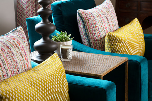 Teal Velvet armchairs. Contrasting yellow and multi colours geometric design cushions.