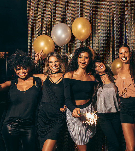 group of women partying and posing in front of a gold stream curtain