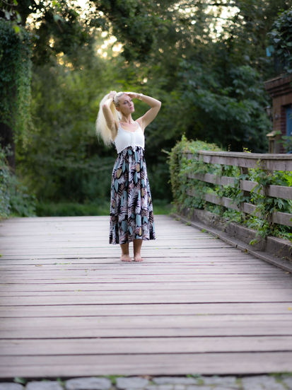 Ganzkörperportrait von Denise auf Holzbrücke, formt ihre Haare zum Pferdeschwanz, verträumter Blick in die Natur, sommerlich, natürlich.