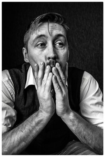 Schwarz-Weiß-Porträt eines Mannes im Sitzen mit dem Kinn in den Händen – inszenierter Moment zwischen Ausdruck und Emotion.
